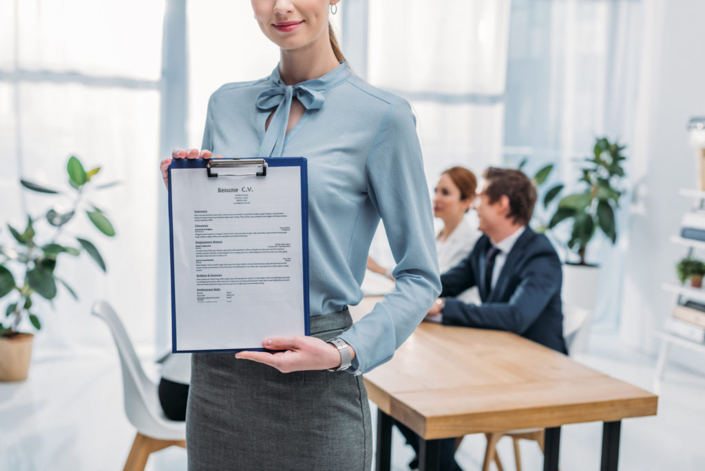 Cheerful recruiter holding clipboard with resume, illustrating recruitment strategy and candidate assessment.