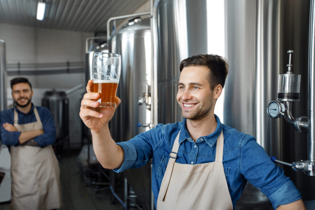 Brewer raising glass in brewery, small business management and operations.