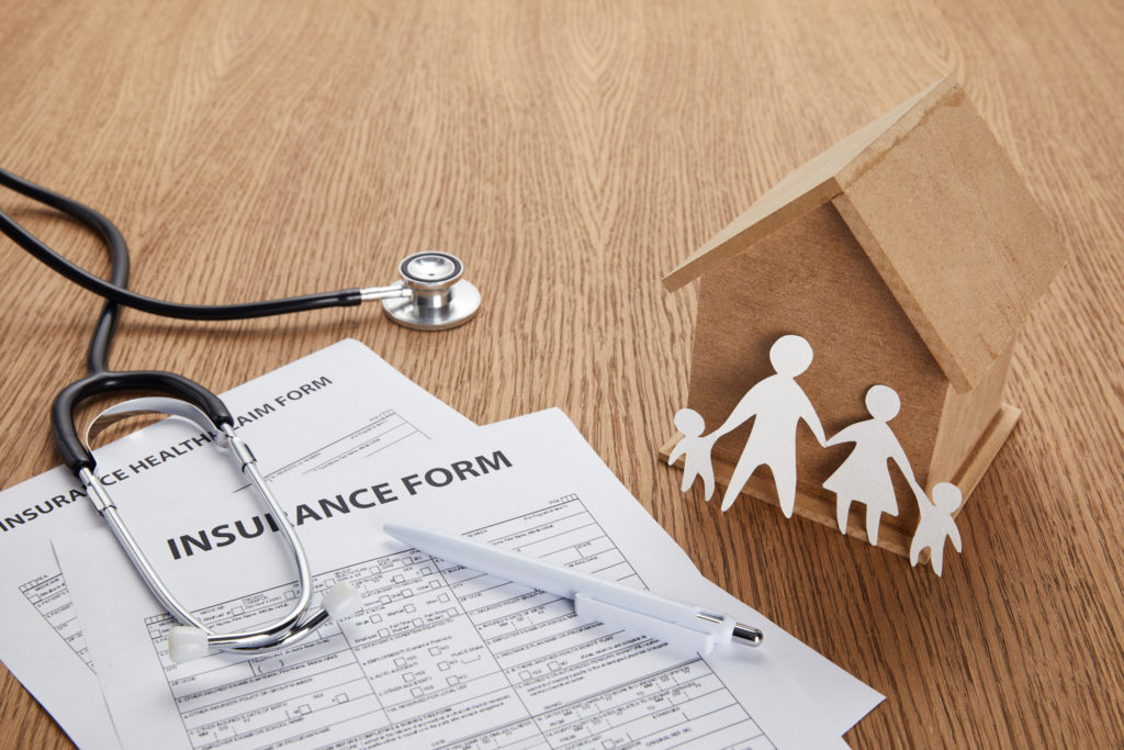 Insurance health claim form and stethoscope with family silhouette representing life insurance protection
