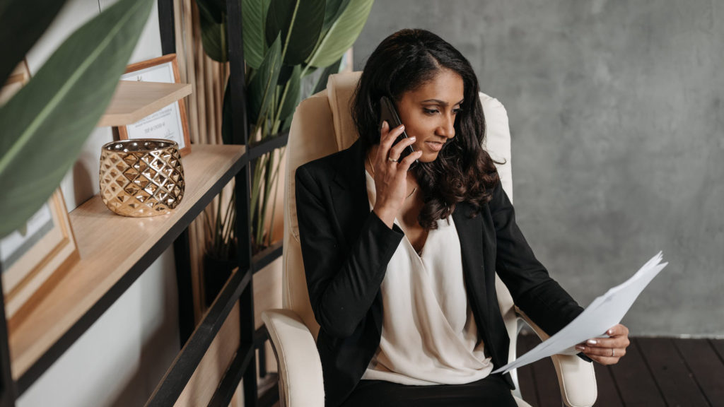 Woman on phone reviewing documents, law firm marketing strategy.