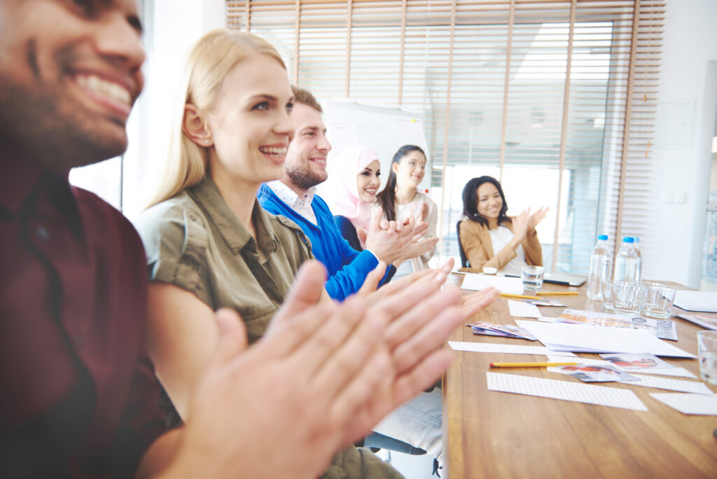 Business team applauding leader in collaborative meeting space.
