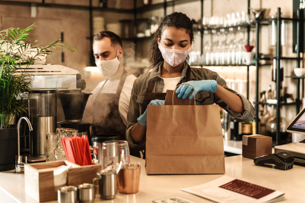 Restaurant owners and staff wearing face masks preparing takeout orders.
