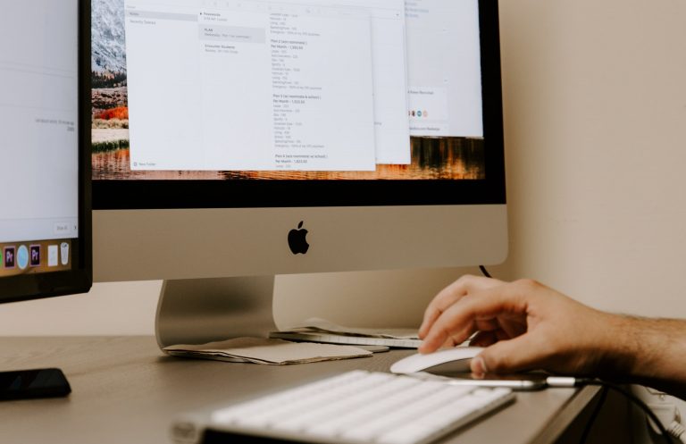 Computer screen displaying code and SEO resources, hand using a mouse for online marketing optimization.