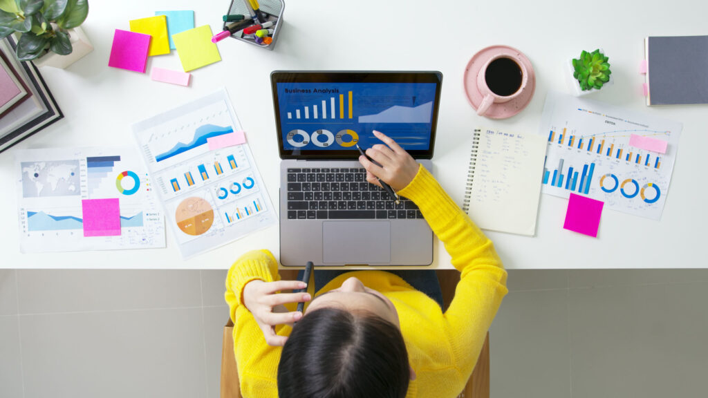 SME owner's desk with laptop displaying SEO charts and graphs, illustrating marketing and business management strategies.