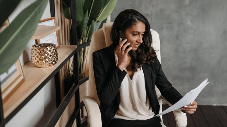 Businesswoman on phone reviewing documents, entrepreneurship resources and advice.