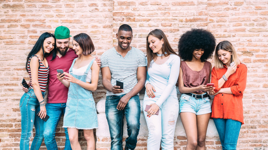 Group of friends using smartphones for marketing and influencer strategies.