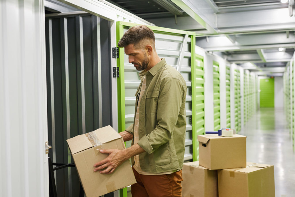 Man storing boxes in a self-storage unit protecting valuable possessions