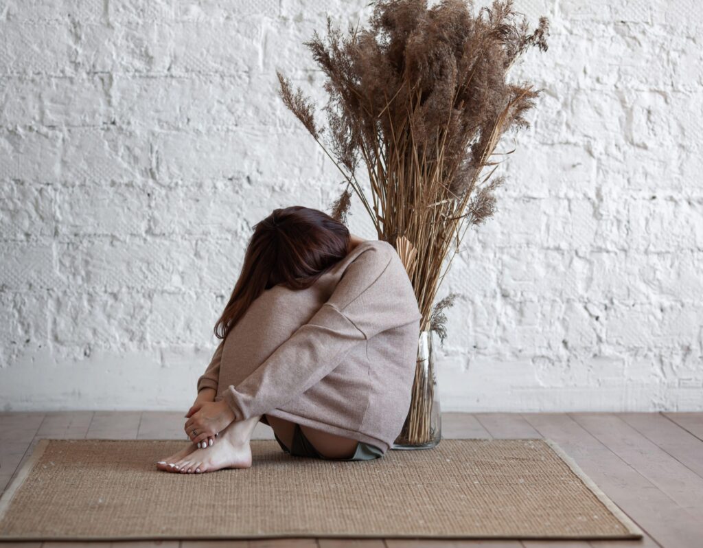 Person with head in hands, expressing sadness and depression, related to physical pain and mental health.