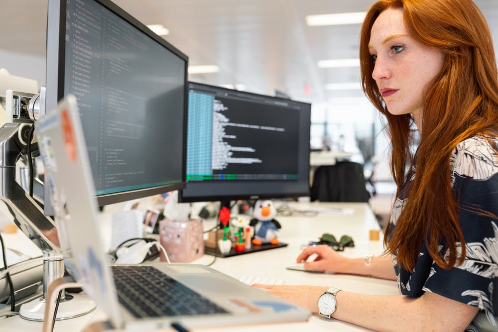 Woman coding on computer illustrating ReactJS development.